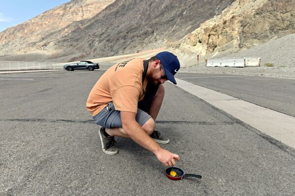   مردی در حال سرخ کردن تخم مرغ روی آسفالت پارک ملی «دره مرگ» ، کالیفرنیا، آمریکا - اسپوتنیک ایران  