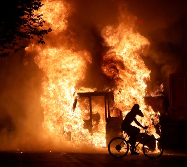 دوچرخه سوار در حال عبور از کنار کامیون آتش گرفته در ایالت ویسکنسین - اسپوتنیک ایران  