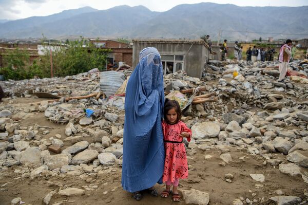 زنی به همراه فرزندش در کناره خرابه پس از وقوع سیل در افغانستان - اسپوتنیک ایران  