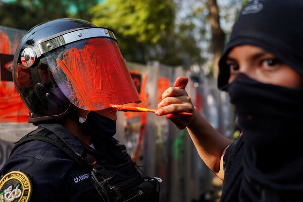دختری در حال رنگ کردن کلاه ایمنی پلیس در تظاهرات علیه تبعیض جنسیتی در مکزیک  - اسپوتنیک ایران  