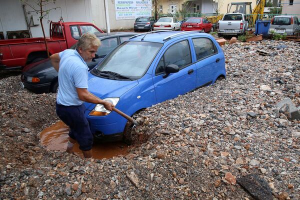 مردی در حال بیرون کشیدن ماشینش بعد از باران شدید در یونان - اسپوتنیک ایران  