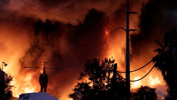 Пожарный стоит на резервуаре с водой во время пожара на заводе по переработке металлолома компании Deacero в Гуадалупе, на окраине Монтеррея, Мексика - اسپوتنیک ایران  