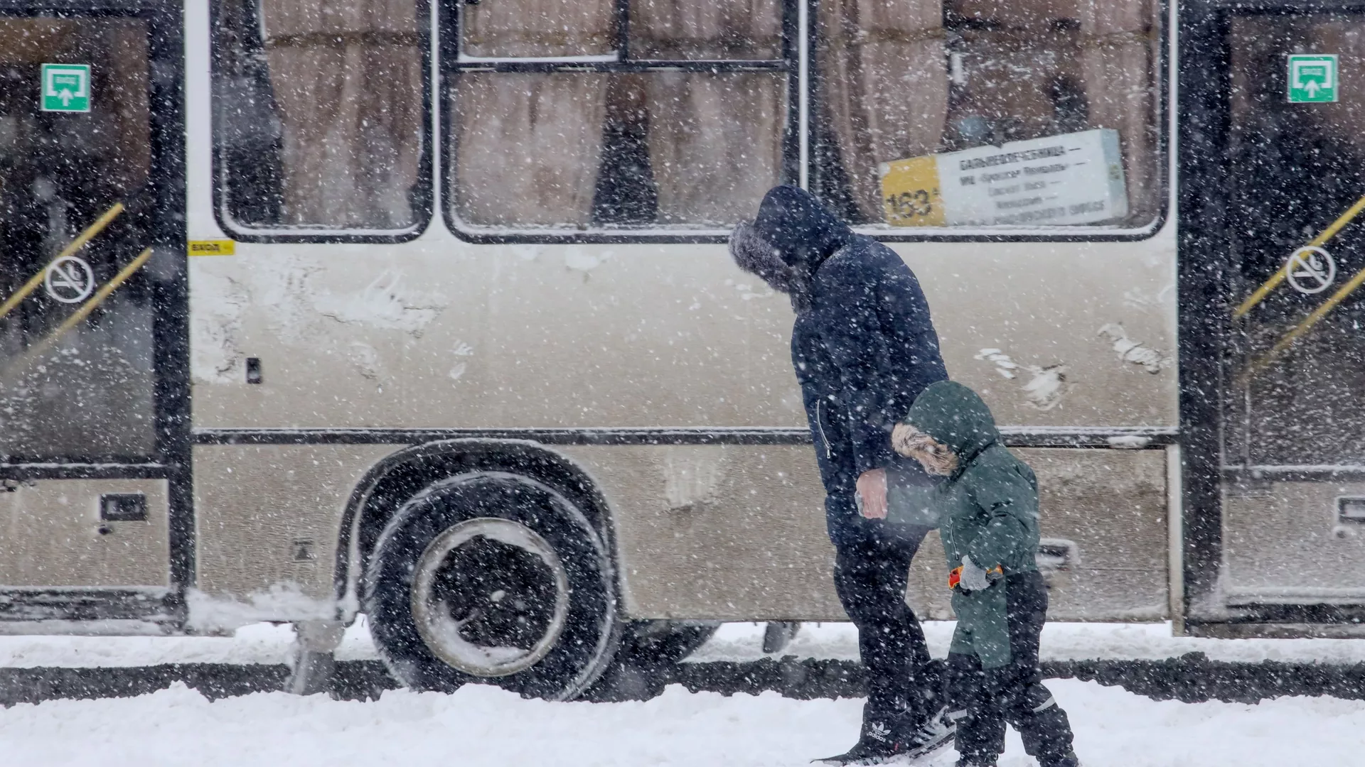 Женщина с ребенком во время снегопада на улице Краснодара