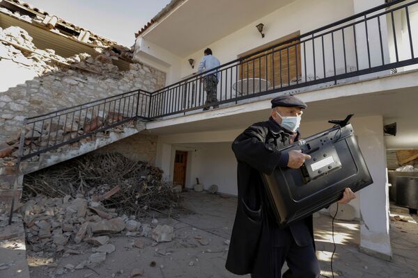 مردی با تلویزیون در بیرون از خانه ای که در اثر زلزله در یونان آسیب دیده است. - اسپوتنیک ایران  
