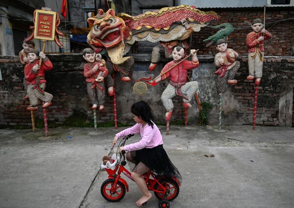 دختری با دوچرخه از کنار اثر هنری با عنوان رقص شیر توسط هنرمند نگوین ژوان لام  Phuc Tan در هانوی عبور می کند  - اسپوتنیک ایران  