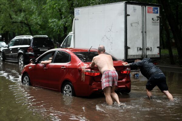 مردی در حال هل دادن ماشینش در خیابان آب گرفته در مسکو - اسپوتنیک ایران  