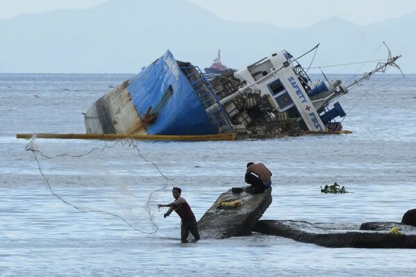 ماهیگیر در کنار کشتی غرق شده در فلیپین - اسپوتنیک ایران  