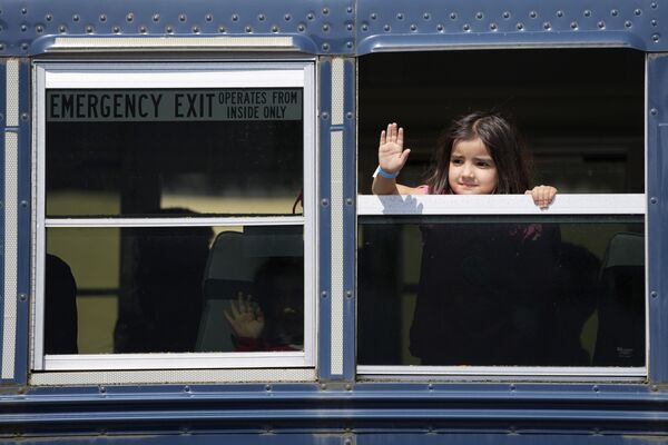 کودک افغان در یکی از اتوبوس ها در پایگاه هوایی رامشتاین در آلمان دست تکان می دهد - اسپوتنیک ایران  