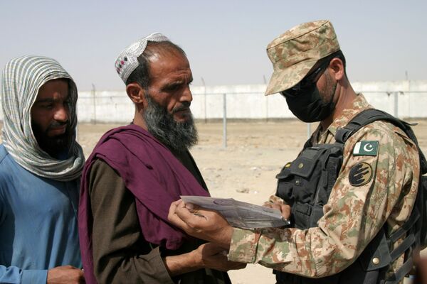سرباز پاکستانی اسناد پناهجویان افغان را در مرکز ایست بازرسی در نزدیکی شهر مرزی چمن پاکستان بررسی می کند - اسپوتنیک ایران  