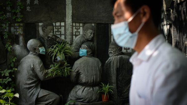 Мужчина проходит мимо скульптур в масках возле ресторана в Пекине - اسپوتنیک ایران  