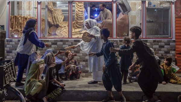 زنی در مقابل نانوایی در کابل بین کودکان نیازمند نان تقسیم می کند - اسپوتنیک ایران  