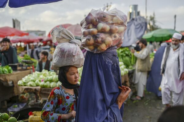 زن افغان با برقع، یک گونی پیاز بر روی سر در بازار کابل حمل می کند - اسپوتنیک ایران  