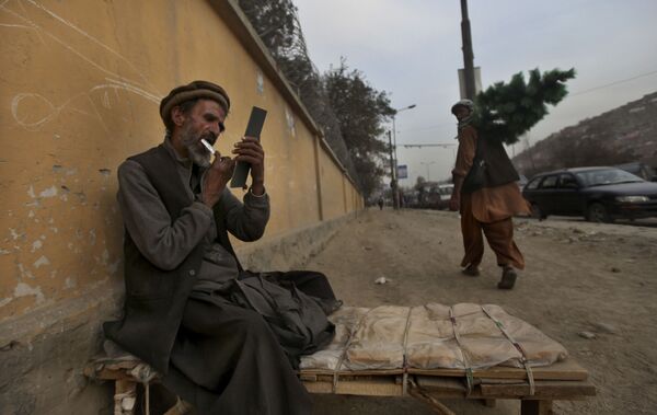 یک آرایشگر کنار جاده در کابل سال ۲۰۱۰ در حالی که منتظر مشتری است، ریش خود را می زند - اسپوتنیک ایران  