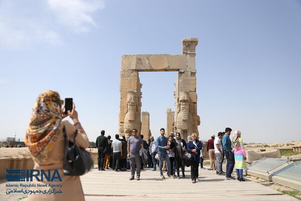 بازدیدکنندگان مقابل دروازه ای در تخت جمشید در حال عکس گرفتن هستند. تخت جمشید کاخ بزرگ شاهان هخامنشی (2500 ق.م) در نزدیکی شیراز است. - اسپوتنیک ایران  