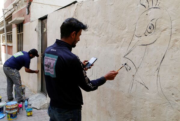 محله های قدیمی بغداد با رقص قلم‌موی نقاشان عراقی، مبدل به تابلوهای زیبای زندگی روزانه می‌شوند.نقاشان هنرمند در حال تغییر چهره دیوارهای محله قدیمی در بغداد. - اسپوتنیک ایران  