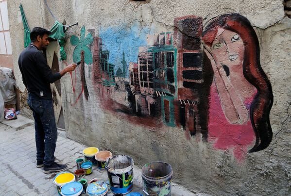 نقاش عراقی داوطلبانه به تغییر چهره دیوار محله قدیمی بغداد مشغول است. - اسپوتنیک ایران  