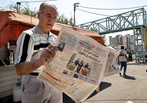 مرد ایرانی روزنامه ای را در دست دارد که خبر عضویت ایران در سازمان همکاری های شانگهای را نشان می دهد - اسپوتنیک ایران  