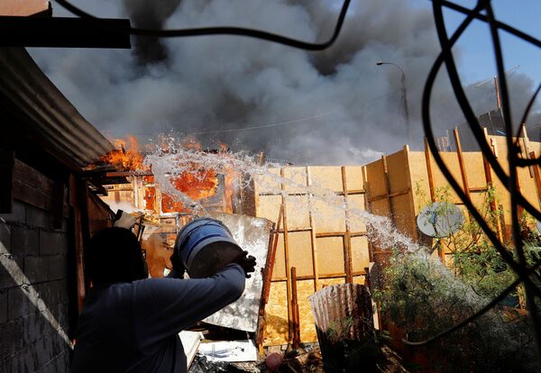 آب پاشیدن ساکن محله برای خاموش کردن آتش در شمال شیلی. - اسپوتنیک ایران  
