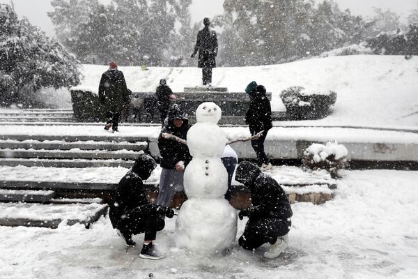 جوانان در هنگام بارش برف سنگین در آتن، یونان، 24 ژانویه 2022، آدم برفی می سازند. - اسپوتنیک ایران  