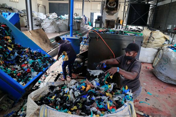کارگران در حال تمیز کردن کیسه های پلاستیکی در نزدیکی مواد پلاستیکی قابل بازیافت در محل تخلیه Dandora در حومه نایروبی، کنیا دیده می شود. - اسپوتنیک ایران  