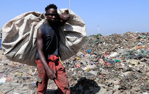 آشغال‌جمع‌کن در نزدیکی مواد پلاستیکی قابل بازیافت در محل تخلیه Dandora در حومه نایروبی، کنیا دیده می شود. - اسپوتنیک ایران  