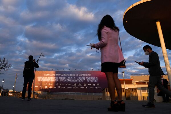 بازدیدکنندگان در روز افتتاحیه MWC (کنگره جهانی موبایل) در بارسلون در 28 فوریه 2022 . سلفی در مقابل بنر نمایشگاه. - اسپوتنیک ایران  