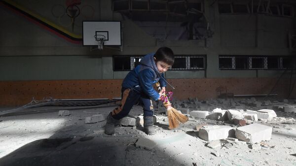 Ребенок подметает мусор в разрушенном спортивном зале специализированной школы с углубленным изучением новогреческого языка в поселке Сартана в Донецкой народной республике - اسپوتنیک ایران  