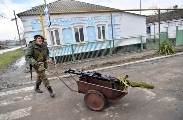 پلیس خلق دونتسک در حال حمل مسلسل سه پایه‌ای در روستای سارتانا. - اسپوتنیک ایران  
