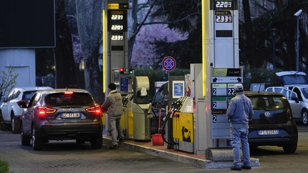 Работник меняет цены на топливо на табло на заправочной станции в Милане - اسپوتنیک ایران  
