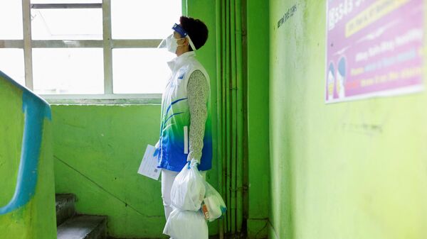 یک داوطلب بسته های ضد اپیدمی را در دست دارد تا در  طول همه گیری ویروس کرونا در هنگ کنگ به ساکنان تحویل بدهد. - اسپوتنیک ایران  
