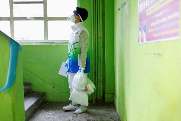 یک داوطلب بسته های ضد اپیدمی را در دست دارد که آن ها را در طول همه گیری ویروس کرونا در هنگ کنگ به ساکنان تحویل می دهد. - اسپوتنیک ایران  