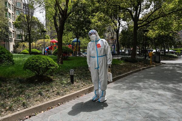 داوطلب در لباس ایمنی در شانگهای در محلی که ساکنان آنجا مورد تست کووید -19 قرار گرفتند. - اسپوتنیک ایران  