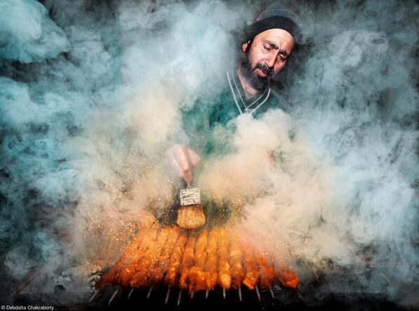 عکسی از یک فروشنده غذای خیابانی که در حال پخت کباب روی اجاق دودی است در مسابقه عکاسی بانوی صورتی 2022.عکاس، دبداتا چاکارابورتی از هند. - اسپوتنیک ایران  