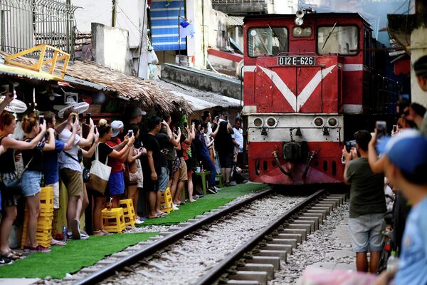 خیابان ریلی در هانوی، یکی از جاذبه های گردشگری ویتنام.گردشگران در حال عکس گرفتن از قطار در حال حرکت در این خیابان تنگ و باریک. - اسپوتنیک ایران  