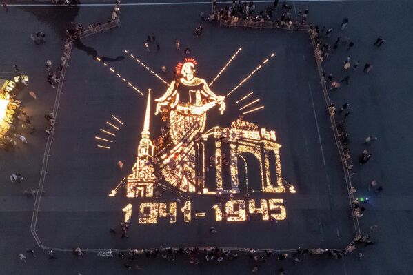 مردم قبل از حمله آلمان نازی به اتحاد جماهیر شوروی در 81 سال پیش در طول جنگ جهانی دوم، در میدان قصر در سن پترزبورگ، شمع هایی را روشن می کنند که بنای یادبود سرزمین مادری را به تصویر می کشد. پترزبورگ، روسیه. - اسپوتنیک ایران  