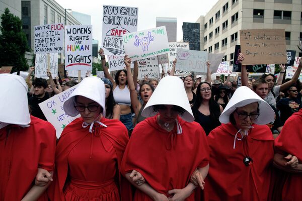 فعالان حقوق سقط جنین، با لباس‌هایی از The Handmaid&#x27;s Tale، معترضان را در طول راهپیمایی در دنور، کلرادو در 27 ژوئن 2022، چهار روز پس از نقض حق سقط جنین توسط دادگاه عالی ایالات متحده رهبری می‌کنند - اسپوتنیک ایران  