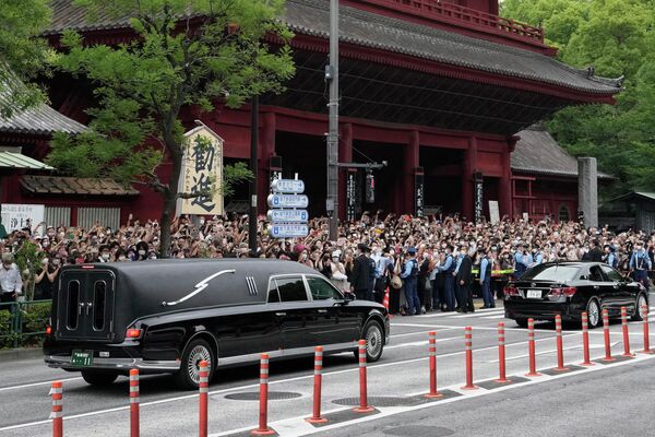 وسیله نقلیه، سمت چپ، حامل جسد شینزو آبه، نخست وزیر سابق ژاپن، معبد زوجوجی را پس از تشییع جنازه وی در توکیو در روز سه شنبه، 12 ژوئیه 2022، ترک می کند - اسپوتنیک ایران  