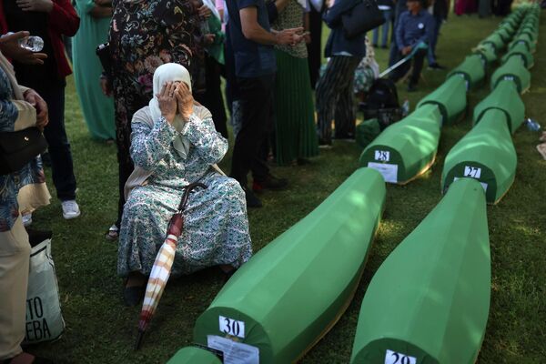 یک زن مسلمان بوسنیایی، در کنار تابوت جسد شوهرش که در میان 50 قربانی تازه شناسایی شده نسل کشی سربرنیتسا در پوتوچاری است، عزاداری می کند، دوشنبه، 11 ژوئیه 2022 - اسپوتنیک ایران  