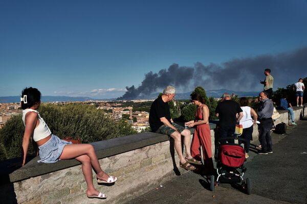 مردم در پیاتزا گاریبالدی در تپه جیانیکولو، به دودی که پس از آتش‌سوزی در نزدیکی پارک باستان‌شناسی منطقه سنتوسل، در شرق رم، در 9 ژوئیه 2022 برمی‌خیزد نگاه می‌کنند - اسپوتنیک ایران  