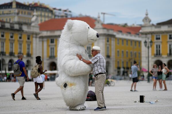 مردی با شخصی که لباس خرس قطبی پوشیده در میدان کومرسیو لیسبون، دوشنبه، 11 ژوئیه 2022 - اسپوتنیک ایران  