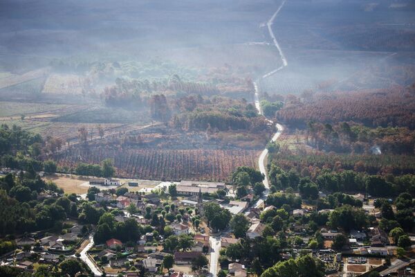 این نمای هوایی که در 29 ژوئیه 2022 گرفته شده است، دود را نشان می دهد که پس از آتش سوزی های جنگلی در کنار روستایی که به لطف آتش نشانان در نزدیکی لندیرس، جنوب غربی فرانسه، حفظ شده است، از بالای جنگل سوخته بلند می شود. - استان ژیروند اعلام کرد که دو آتش سوزی که طی 10 روز گذشته 20800 هکتار از جنگل های ژیروند را از بین برده و منجر به تخلیه بیش از 36000 نفر شده است، رفع شده است اما آتش نشانان همچنان باید در محل بمانند تا بر وقوع دوباره آن نظارت کنند. - اسپوتنیک ایران  