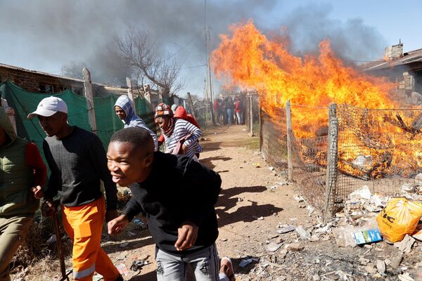 اعضای جامعه مهلکنگ از آتش سوزی وسایل معدنچیان مشکوک غیرقانونی در خوابگاه Mohlakeng در نزدیکی Randfontein فرار می کنند. - اسپوتنیک ایران  