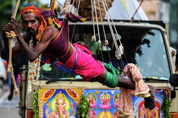 یک طرفدار هندو تامیل در حالی که قلاب‌ها در بدنش آویزان شده است، در جشنواره هندوئیسم Vel در کلمبو شرکت می‌کند. - اسپوتنیک ایران  