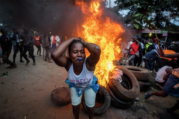 یکی از حامیان کاندیدای ریاست جمهوری رایلا اودینگا هنگام اعتراض در کنار جاده ای از لاستیک های سوخته در محله کیبرا در نایروبی، کنیا، سوت می زند. - اسپوتنیک ایران  