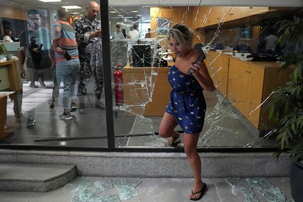 یک کارمند بانک از طریق پنجره ای که توسط مهاجمان در بیروت، لبنان شکسته شده بود، بانک را ترک می کند. - اسپوتنیک ایران  