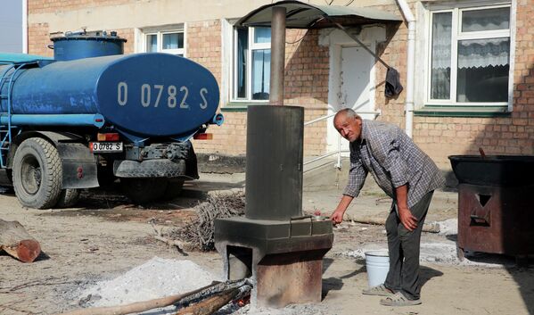 یک پناهجو در خیابانی در روستای بوز آدیر در قرقیزستان آب آشامیدنی را می جوشاند. در 16 سپتامبر 2022 درگیری های گسترده در مرز قرقیزستان و تاجیکستان آغاز شد. - اسپوتنیک ایران  