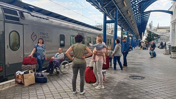 مسافران روی سکوی ایستگاه راه آهن در سواستوپل منتظر سوار شدن به اولین قطار سواستوپل سنت پترزبورگ هستند که از روی پل کریمه عبور می کند. - اسپوتنیک ایران  