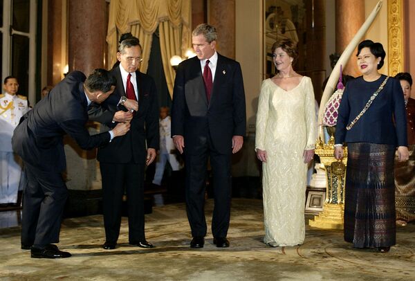 رئیس جمهور ایالات متحده جورج دبلیو بوش، بانوی اول و ملکه سیریکیت تایلند در حال درست کردن کراوات پادشاه بومیبول در اتاق گالری کینگ در کاخ بزرگ در 19 اکتبر 2003 در بانکوک. - اسپوتنیک ایران  