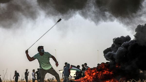 Палестинский протестующий бросает камни на границе с Израилем в районе города Газа - اسپوتنیک ایران  