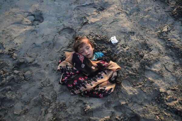 دختری که توسط والدینش در ساحل پوشیده از شن شده است، با این باور که که نور خورشید در التیام بیماری او کمک می کند. کراچی پاکستان، 25 اکتبر - اسپوتنیک ایران  